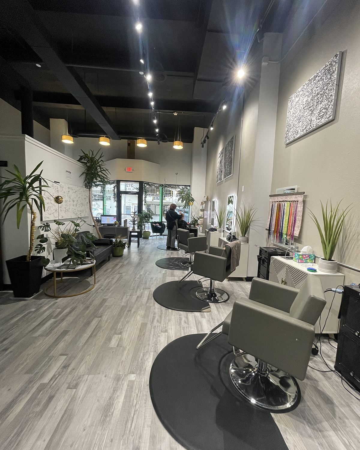 The salon floor at Empire in downtown Billings: styling chairs, plants, a lounge, art on the walls and a stylist at work